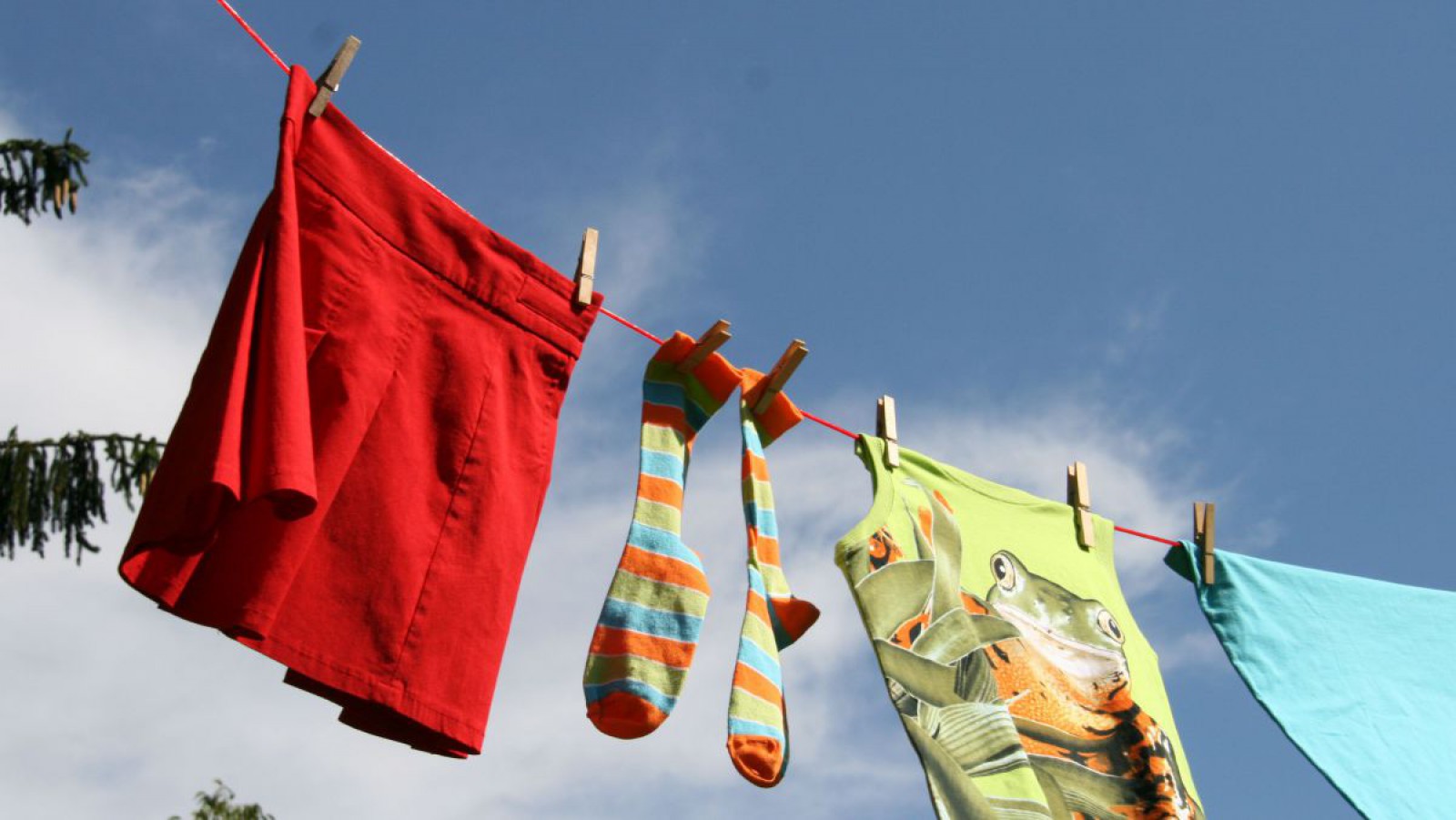 Verschiedene Kleidungsstücke auf einer Wäscheleine im Freien.